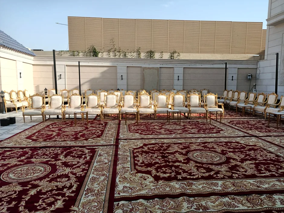 سجاد أحمر مزخرف وكراسي موزعة في ساحة خارجية