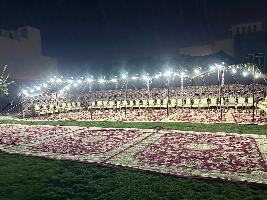 سلاسل إضاءة فوق مساحة استقبال ليلية مزينة بالسجاد والعشب