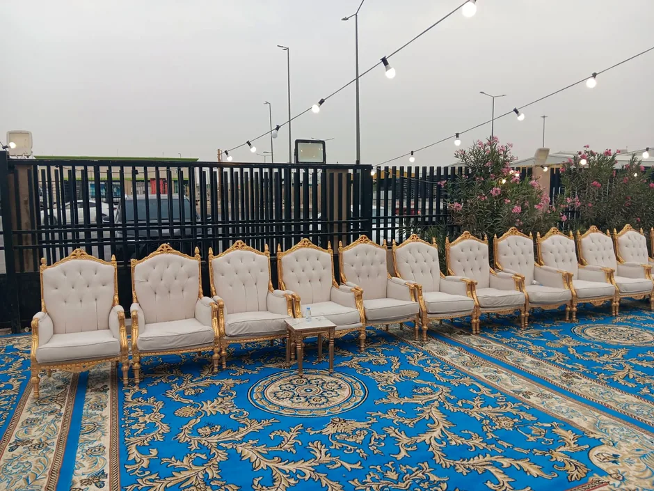 صفوف كراسي ذهبية على سجاد أزرق في فناء خارجي
