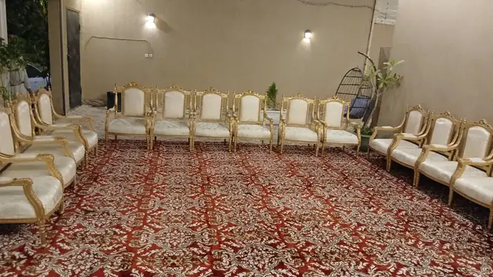 جلسة استقبال تضم مقاعد ذهبية بكسوة فاتحة حول سجاد أحمر مزخرف